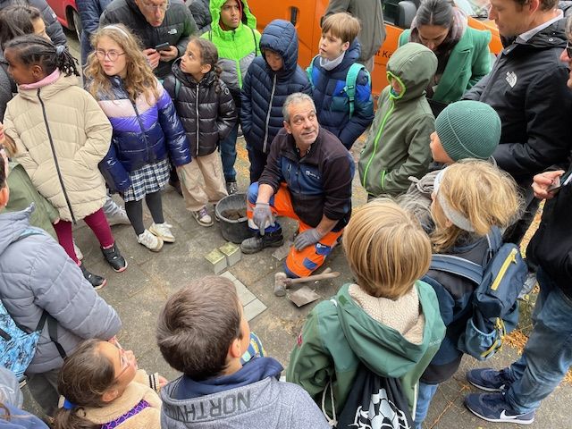 Kinder sind versammelt um die Stelle, an der Stolpersteine verlegt werden