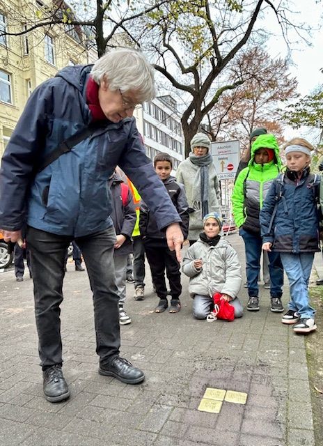 Ein Mann weist im Gedenken auf die drei Stolpersteine