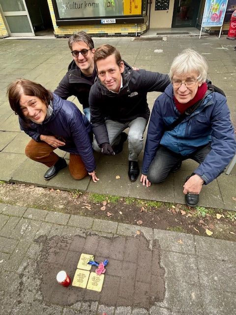 Vier Menschen hocken vor den drei Stolpersteinen