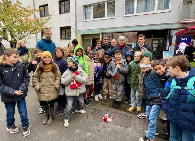 Menschen stehen um die drei Stolpersteine