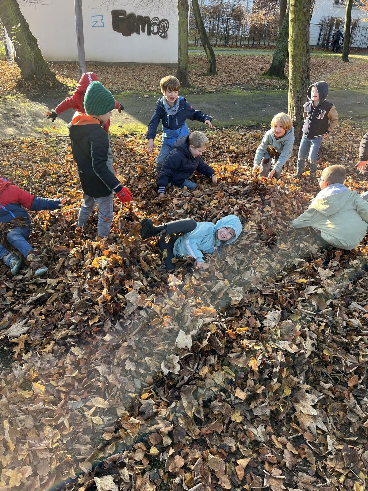 Kinder spielen im Laubhaufen