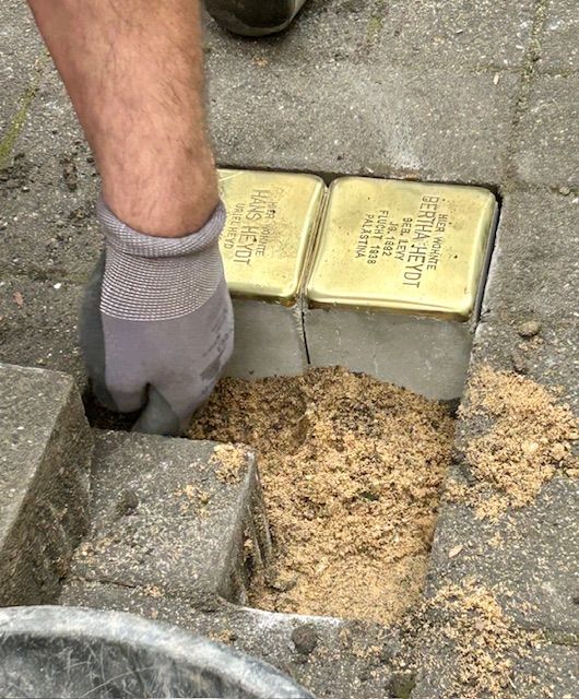 Eine Hand verlegt Stolpersteine