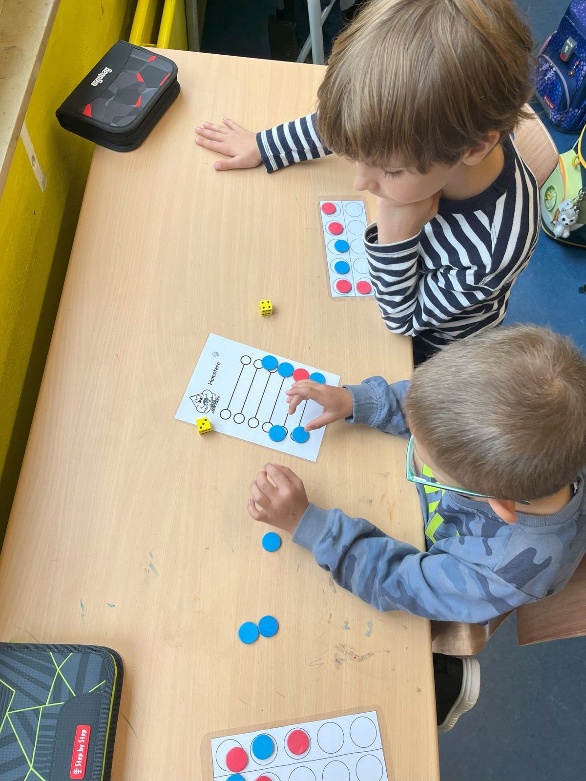 Zwei Kinder spielen Hamstern am Tisch