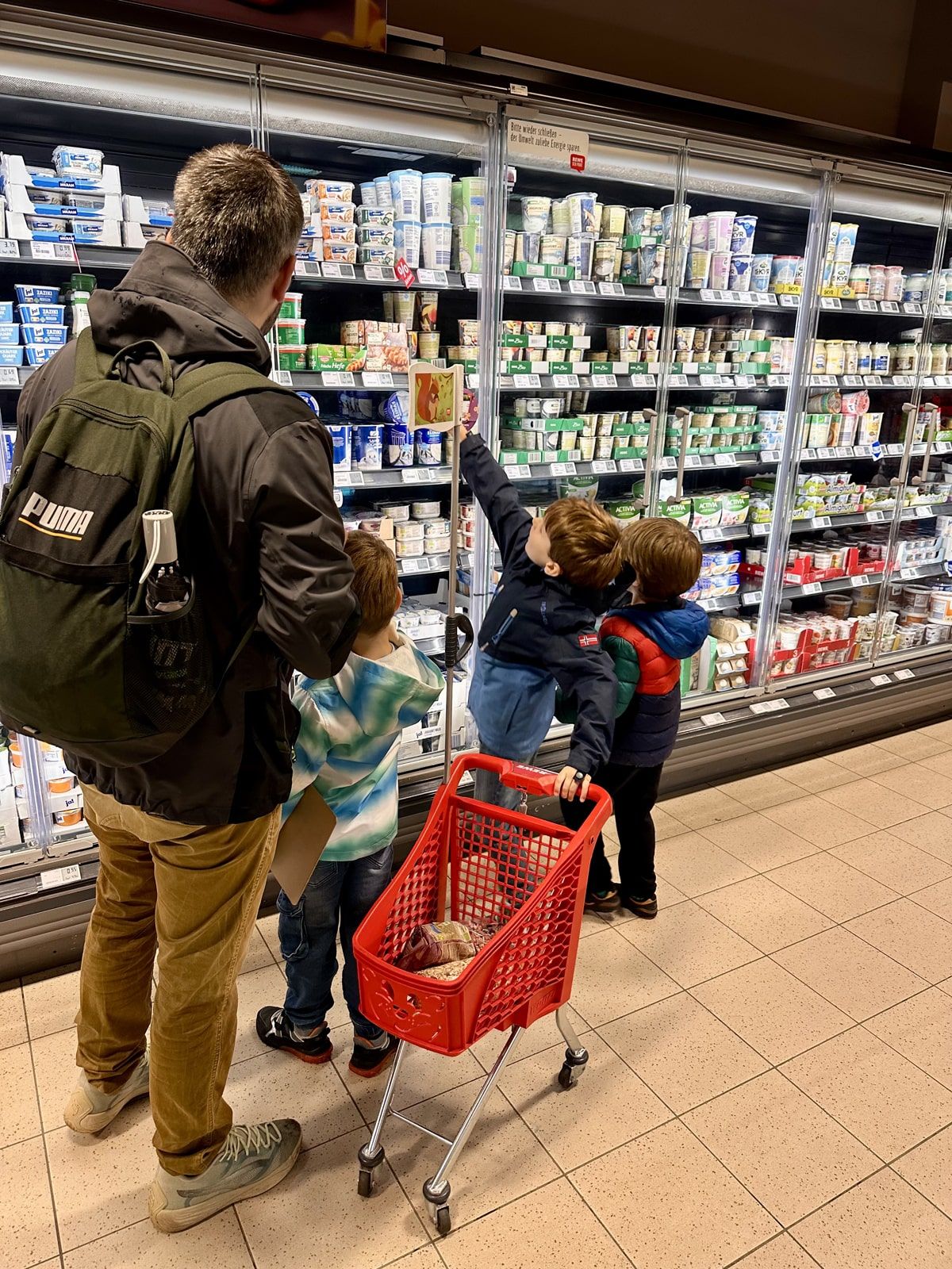 Ein Erwachsener und drei Kinder kaufen im Supermarkt ein