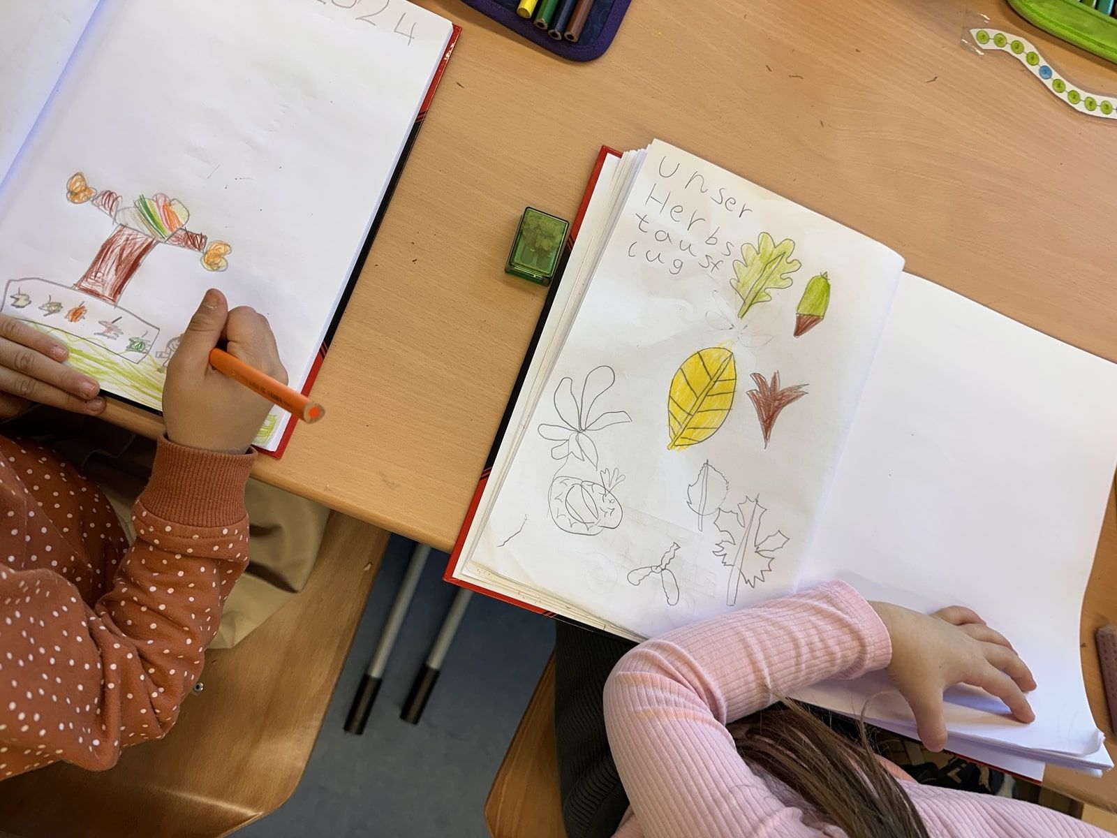 zwei Kinder malen und schreiben in ein Heft in der Schule