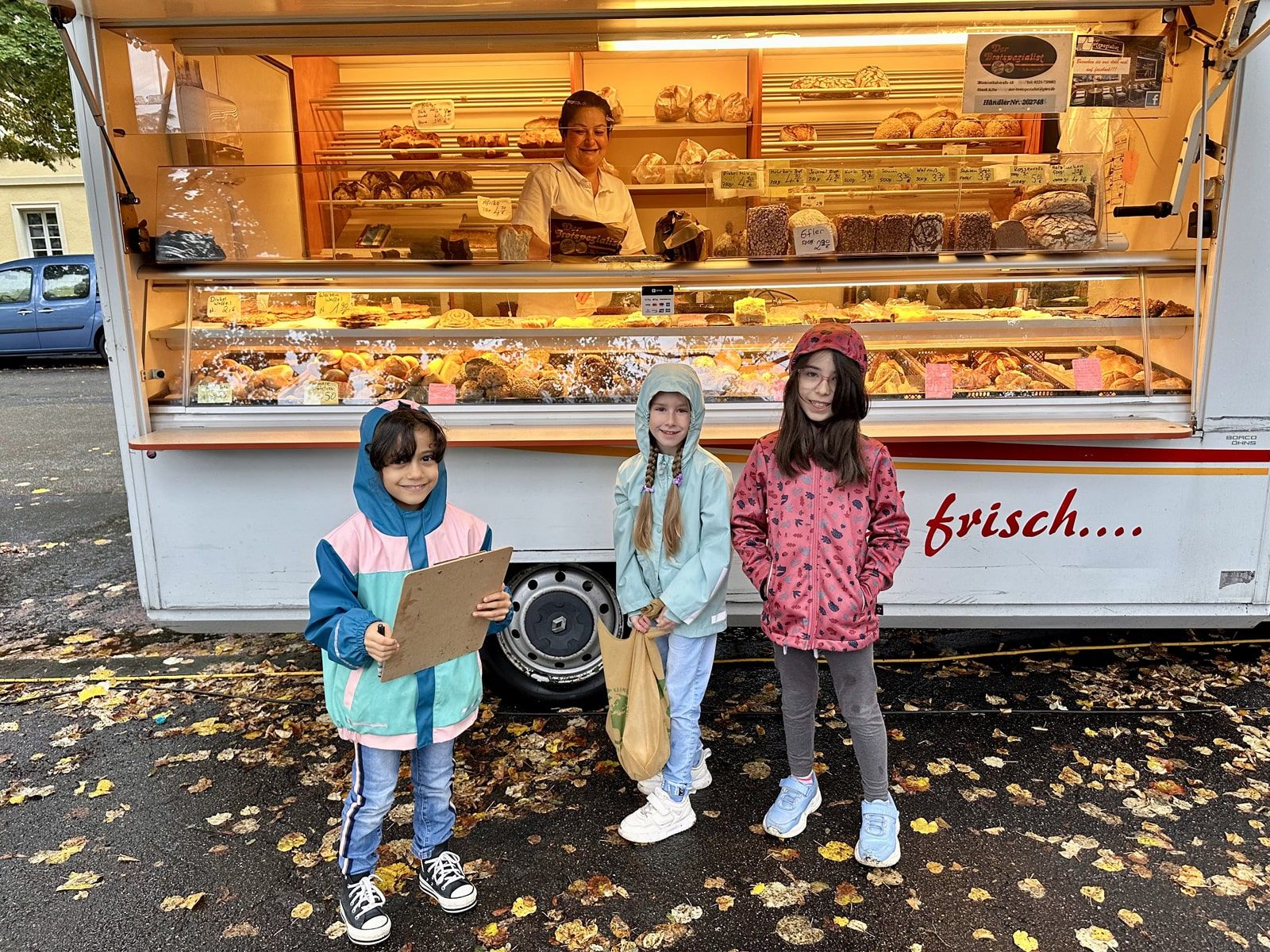 Drei Kinder vor einem Bäckerei-Stand