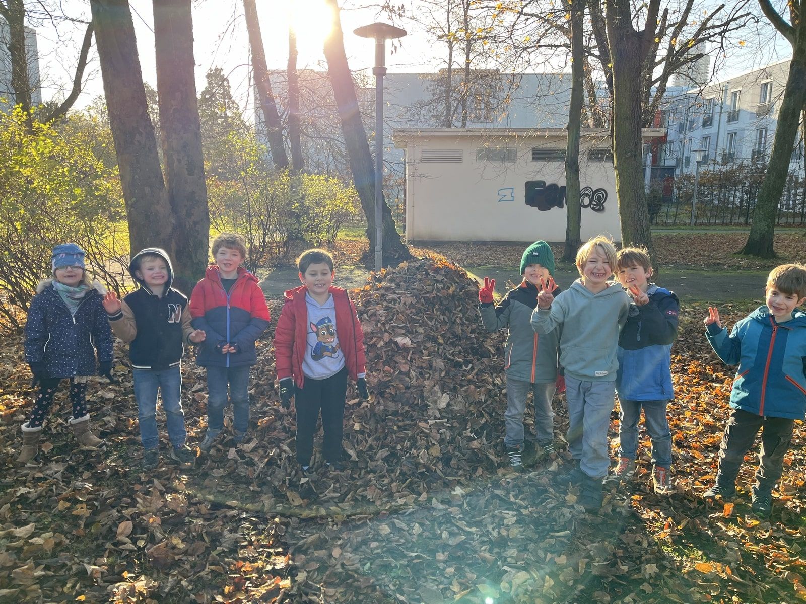 Mehrere Kinder stehen vor einem Laubhaufen