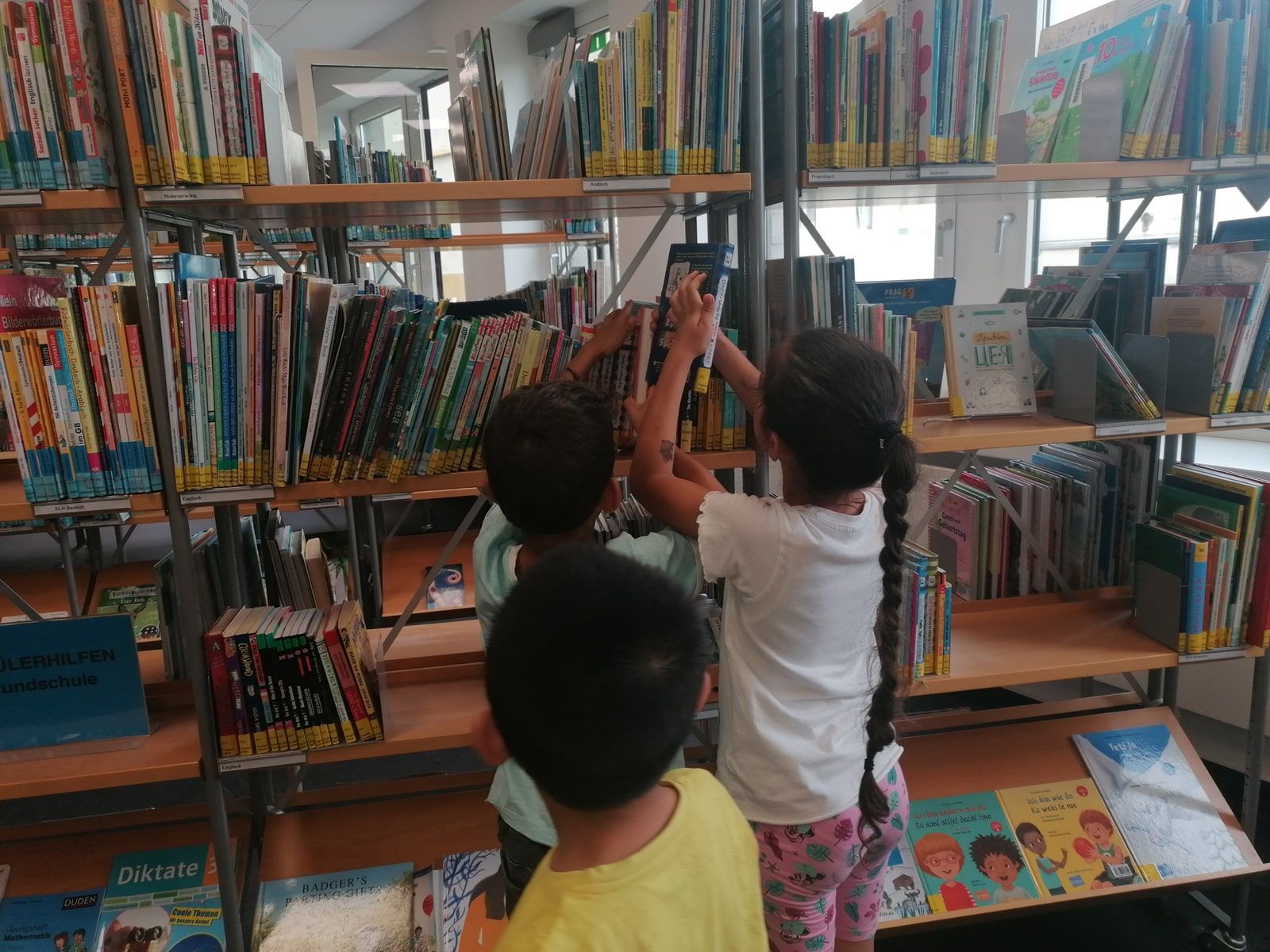 Kinder nehmen sich ein Buch in der Bibliothek