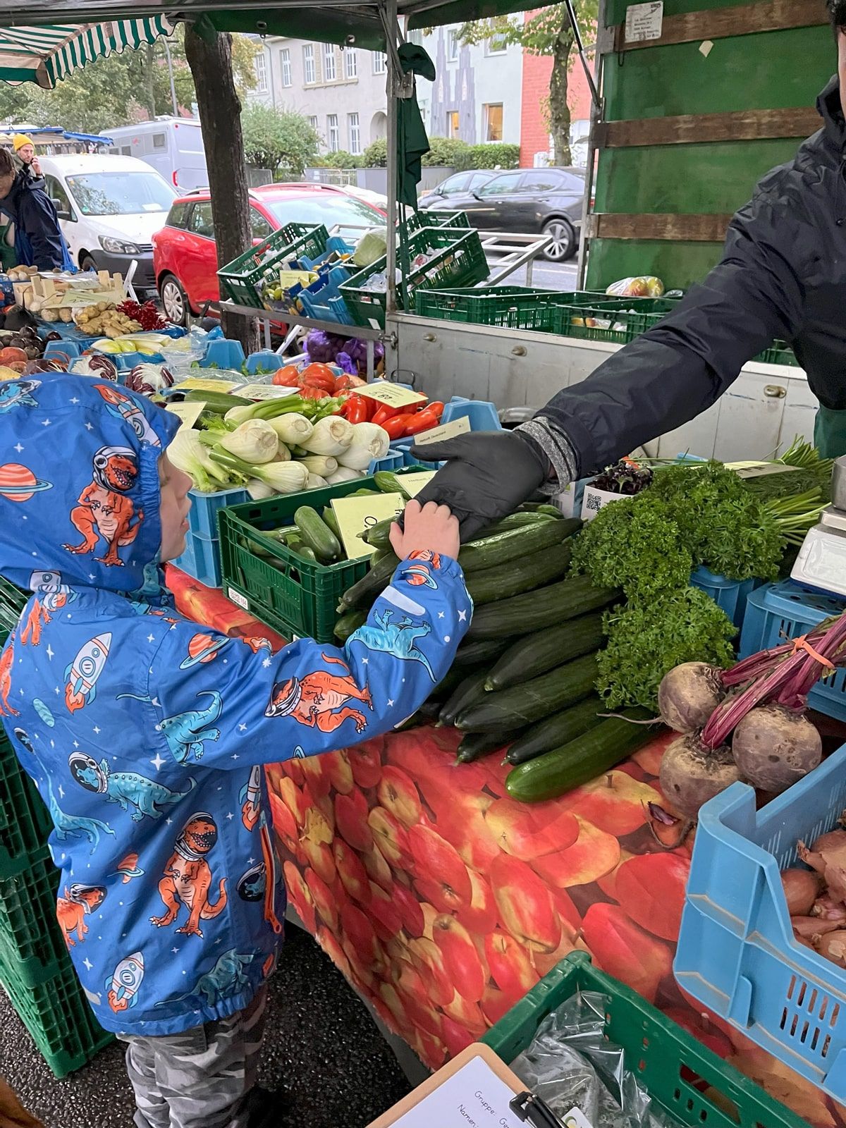 Ein Kinde bezahlt an einem Obst- und Gemüse-Stand