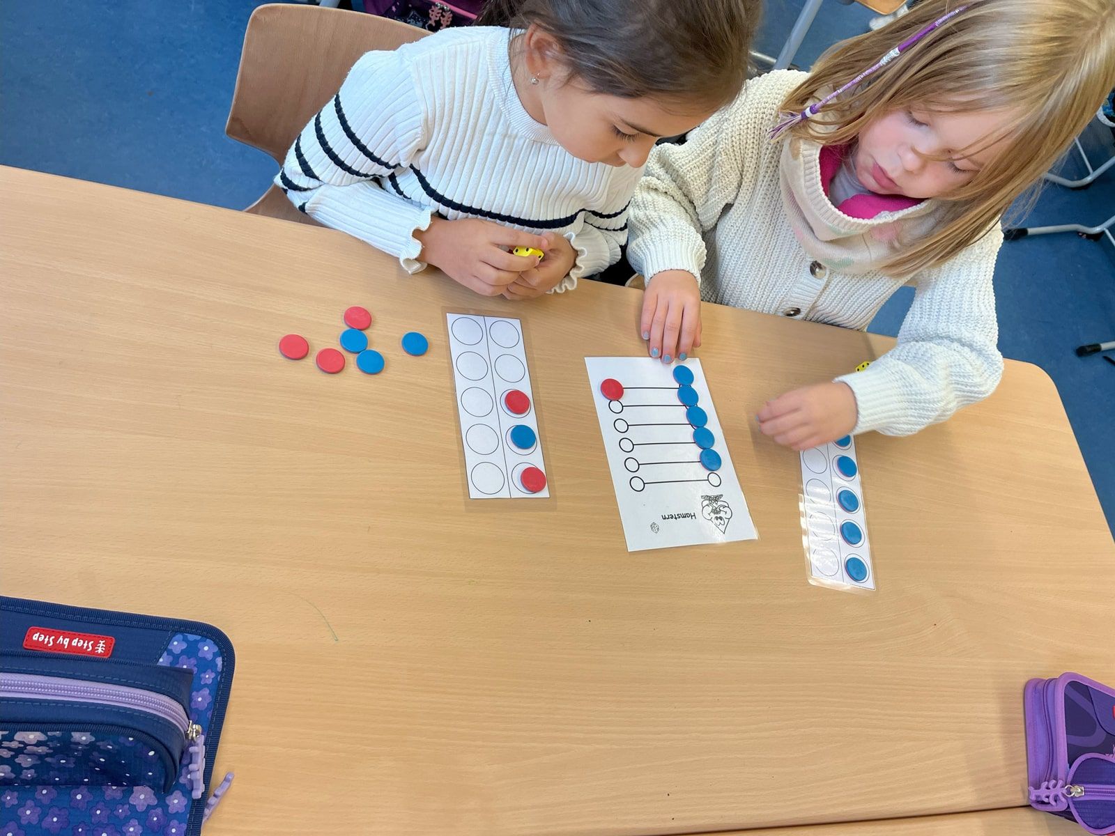 Zwei Kinder spielen Hamstern am Tisch