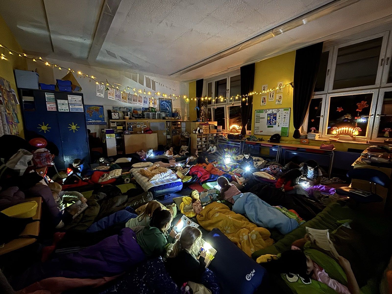 Kinder mit Taschenlampen lesen Bücher in ihren Schlafsäcken