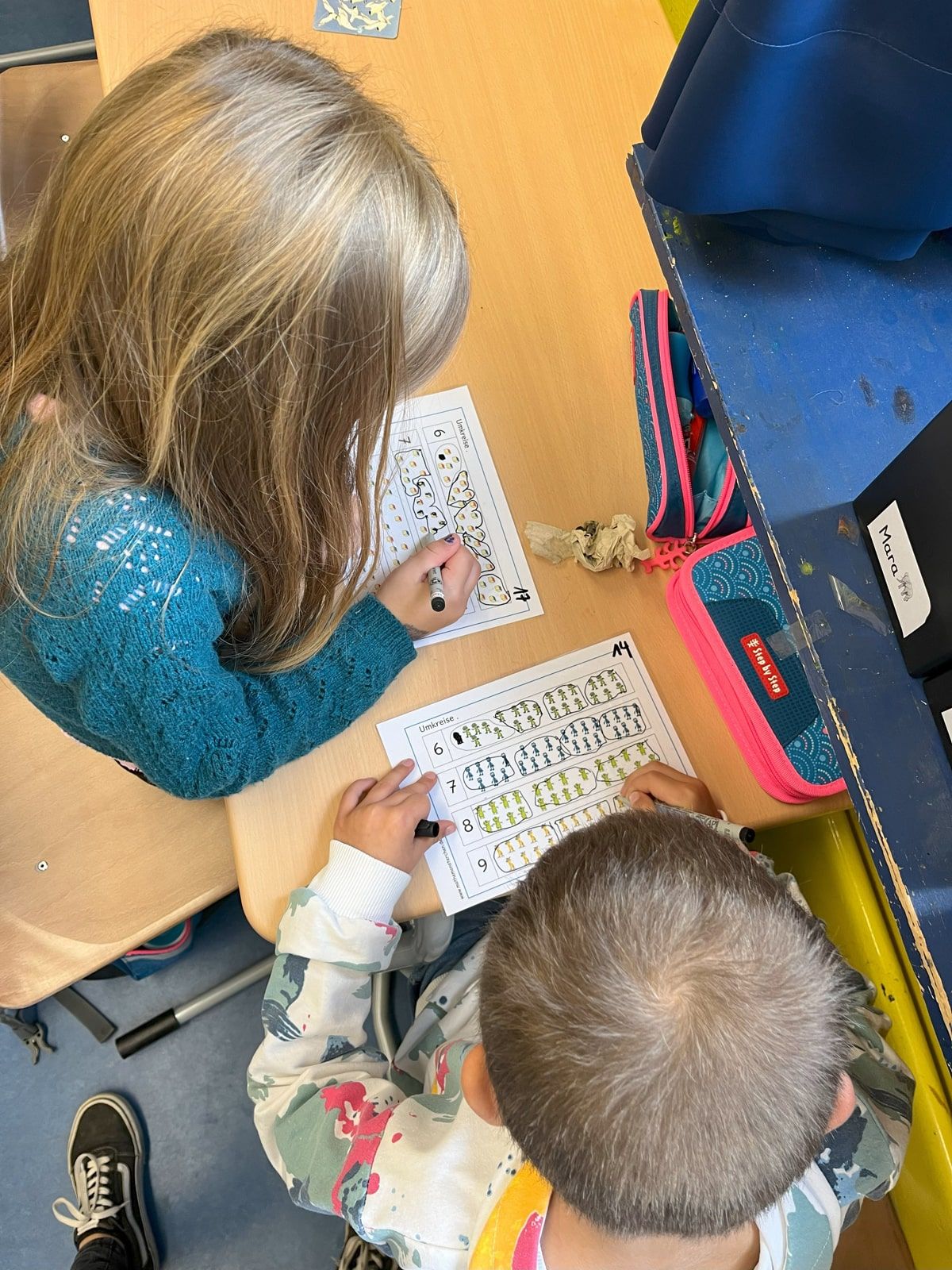 Zwei Kinder kreisen Zahlen auf einer Karte ein