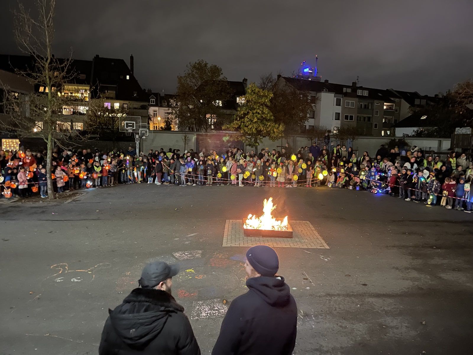 kleines Martinsfeuer auf dem Schulhof umgeben von Kindern